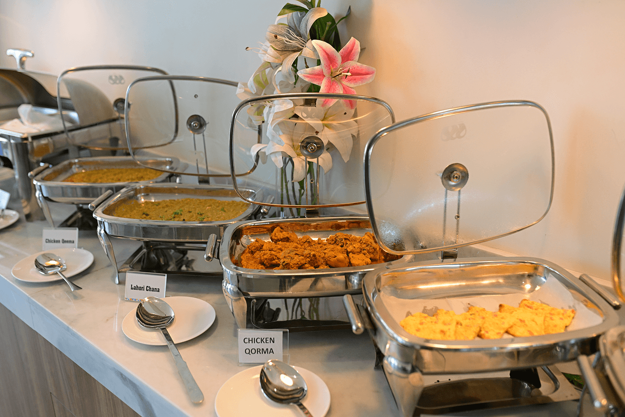 Breakfast buffet at Cyrus One with labeled dishes including Chicken Qorma and Lahori Chana, part of the hotel's complimentary breakfast.
