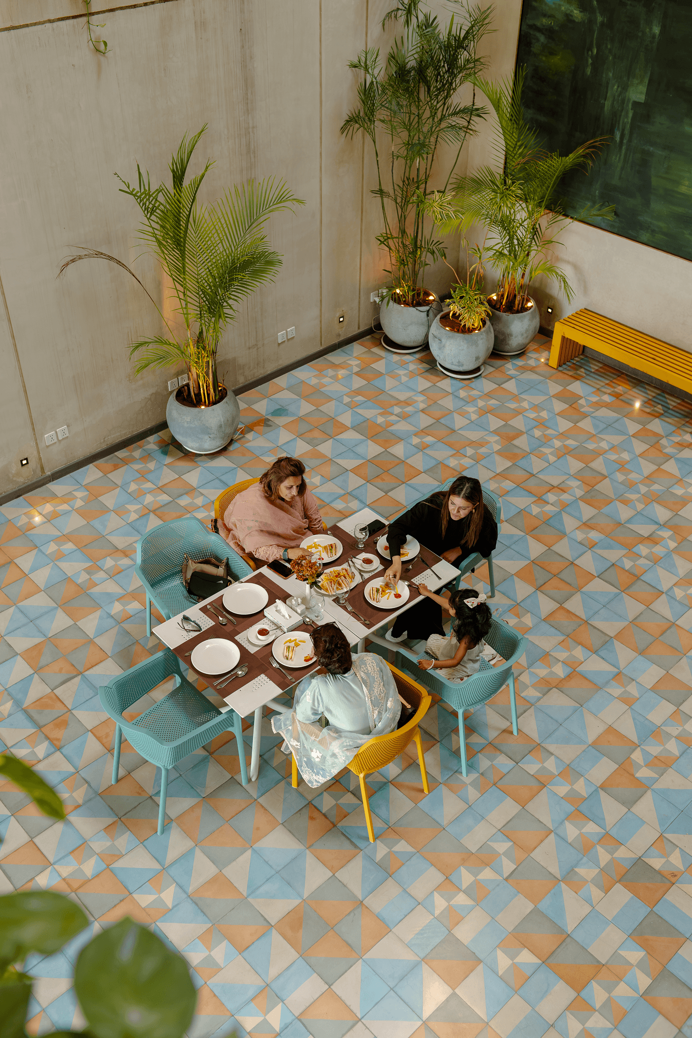 Aerial view of a family dining together at Cyrus One's tiled courtyard, reflecting the hotel's family-friendly accommodation in Islamabad.