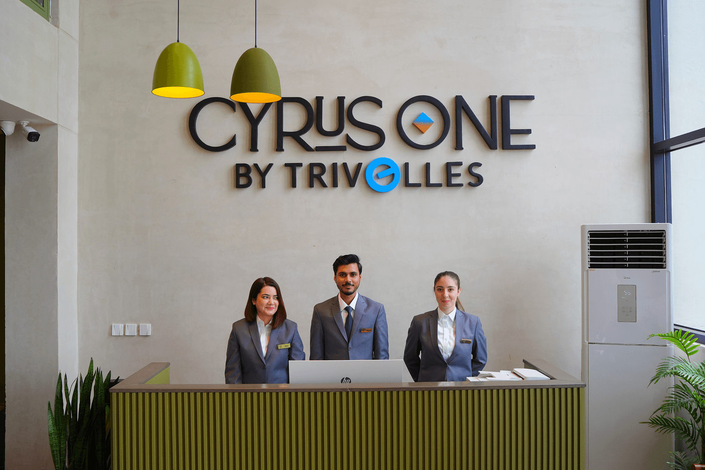 Three uniformed staff at the Cyrus One by Trivelles front desk, reflecting the hotel's 24/7 reception service near Islamabad Airport.